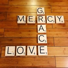 scrabble tiles spelling out the words go, mercy, mac love on a wood floor