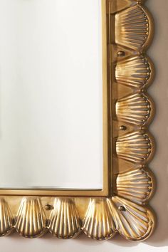 a gold framed mirror with scallops on the edges