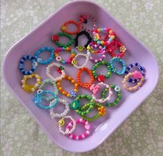 a pink bowl filled with lots of different colored bracelets on top of a table