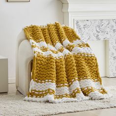 a crocheted blanket sitting on top of a white couch next to a fireplace