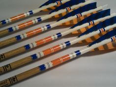 several arrows are lined up on a white surface with blue and orange markers in them