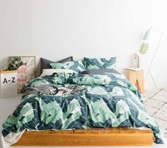 a bedroom with a bed covered in a green leafy comforter and matching pillows