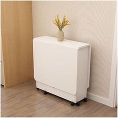 a white cabinet sitting next to a wall with a vase on it's top