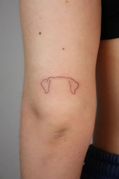 a small tattoo on the back of a woman's left thigh, depicting a dog