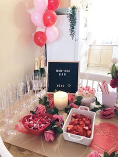 a table topped with lots of pink flowers and balloons