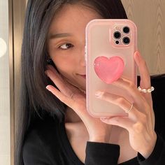 a woman holding up her phone case with a heart on it