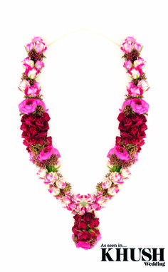 a necklace with pink flowers and pearls on it's sides, in the shape of a heart