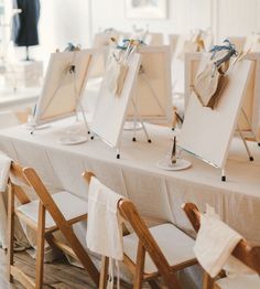 there are many easels on the table with white linens