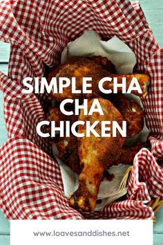 a basket filled with chicken sitting on top of a wooden table next to a red and white checkered cloth