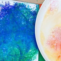 a white plate sitting on top of a table next to a blue and green painting