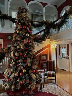 a decorated christmas tree in the middle of a living room with red and gold decorations