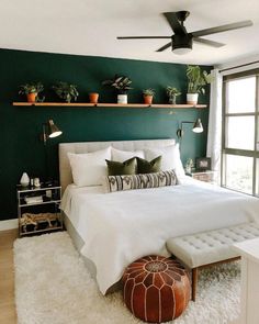 a bedroom with green walls, white bedding and potted plants on the wall