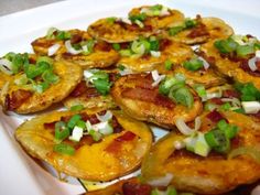 a white plate topped with potato wedges covered in bacon and green onions