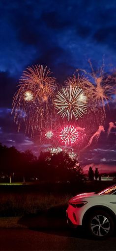 fireworks are lit up in the sky above a car