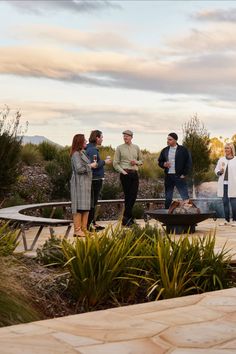 a group of people standing around a fire pit