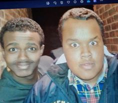 two young men are smiling and posing for a photo on the screen in front of them