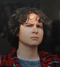 a close up of a person wearing a red and black checkered shirt with frecky hair