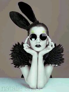 a woman wearing sunglasses and bunny ears with her hands on her head, posing for the camera