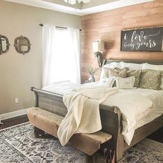 a bedroom with a large bed and lots of pillows on the headboard, along with an area rug