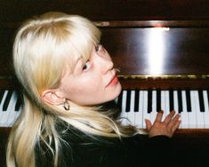 a woman sitting at a piano with her hand on the keys