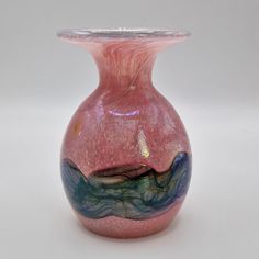 a pink and blue vase sitting on top of a table