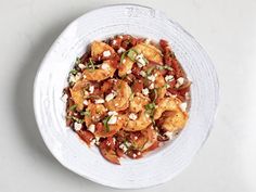 a white bowl filled with shrimp and garnish on top of a marble table