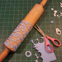 a pair of pink scissors sitting on top of a cutting board next to some cut outs