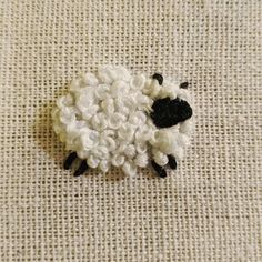 a white sheep with black face sitting on a piece of fabric