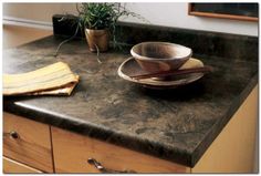 a kitchen counter top with a bowl and saucer on it, next to a potted plant