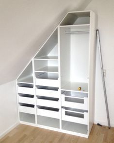 an attic bedroom with white drawers and shelves