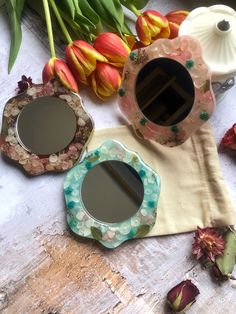 three mirrors sitting on top of a table next to tulips and other flowers