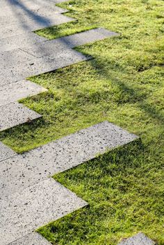 the grass is growing on the sidewalk and it looks like stepping stones are coming out of the ground