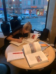 a woman is sitting at a table with books