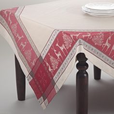 a red and white table cloth with deers on it, sitting on top of wooden legs