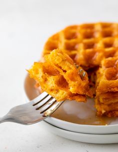 a waffle on a plate with a fork sticking out of the top one side