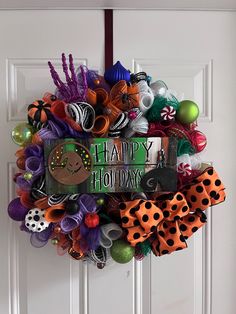 a wreath is hanging on the front door decorated with halloween decorations and ribbon bow ties