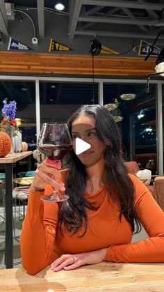 a woman sitting at a table with a glass of wine in front of her face