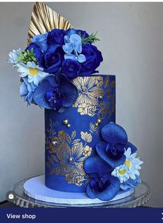 a blue and gold cake with flowers on top