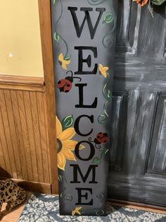 a welcome sign with flowers and ladybugs on it in front of a door