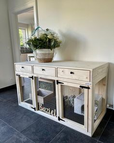 a wooden cabinet with two doors and some baskets on the top, in front of a mirror