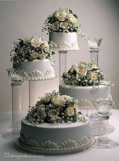 three tiered wedding cake with white flowers on top and wine glasses next to it