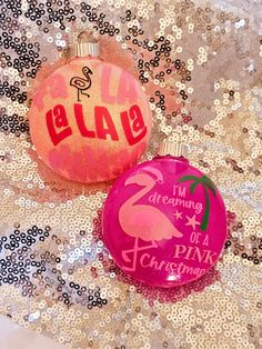 two pink christmas ornaments with flamingos on them