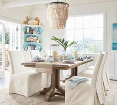 a dining room table with chairs and a chandelier hanging from it's ceiling