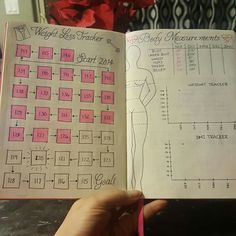 a hand holding an open planner with measurements and body measurements on the page in front of it