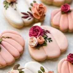 decorated cookies with pink frosting and flowers on them sitting on top of a table