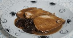 two pieces of meat covered in gravy on a white plate with black dots