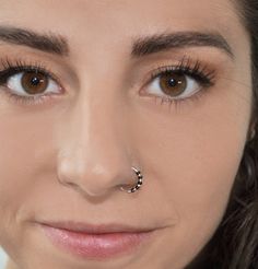 a close up of a woman with a nose ring on her nose and an eye piercing