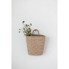 a wicker basket with flowers in it hanging on the wall next to a white wall