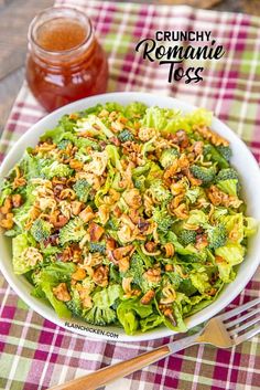 a white bowl filled with broccoli and nuts next to a jar of honey