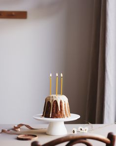 a cake sitting on top of a white plate next to a wooden spoon and fork